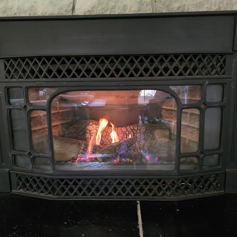 Traditional cast-iron style gas insert with lattice grilles, flames lit